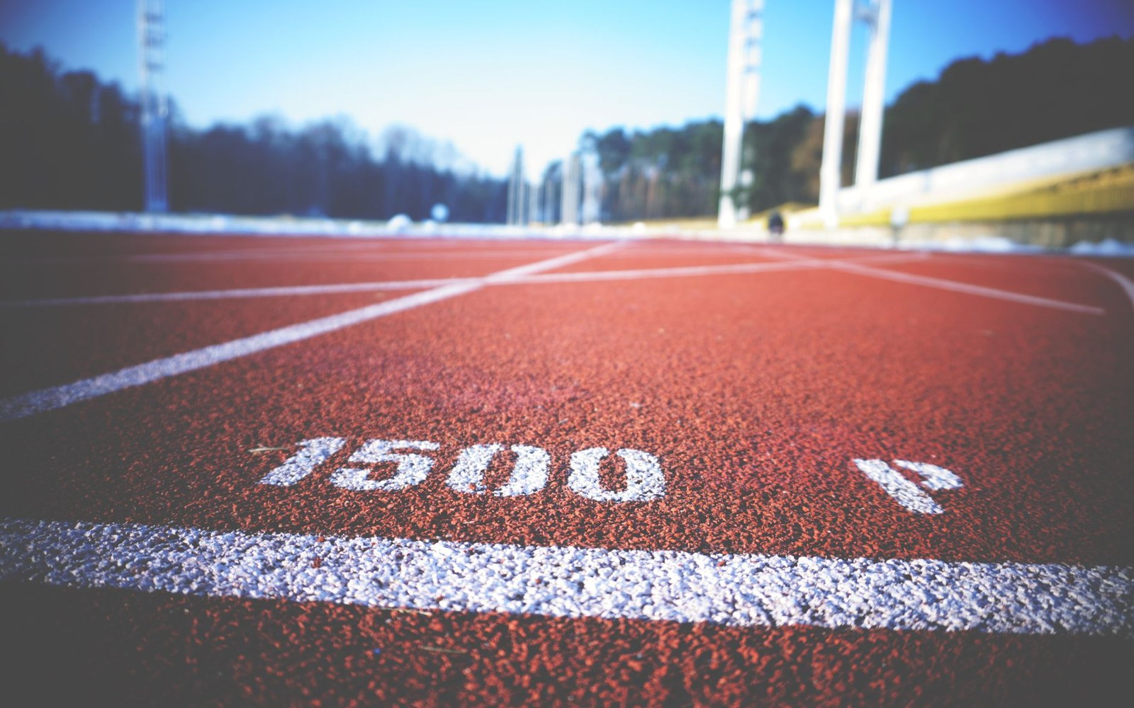 Close-up of a red running track showing the 1500 meter start line marking