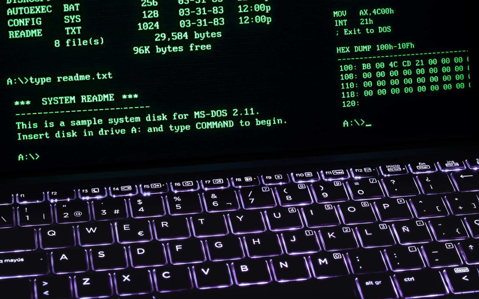 Green MS-DOS command line text and hex dump displayed above a backlit laptop keyboard
